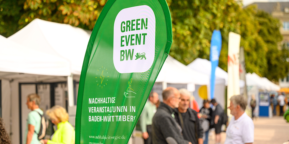 Dropflag mit dem Logo von Green Event BW mit Pavillions im Hintergrund.