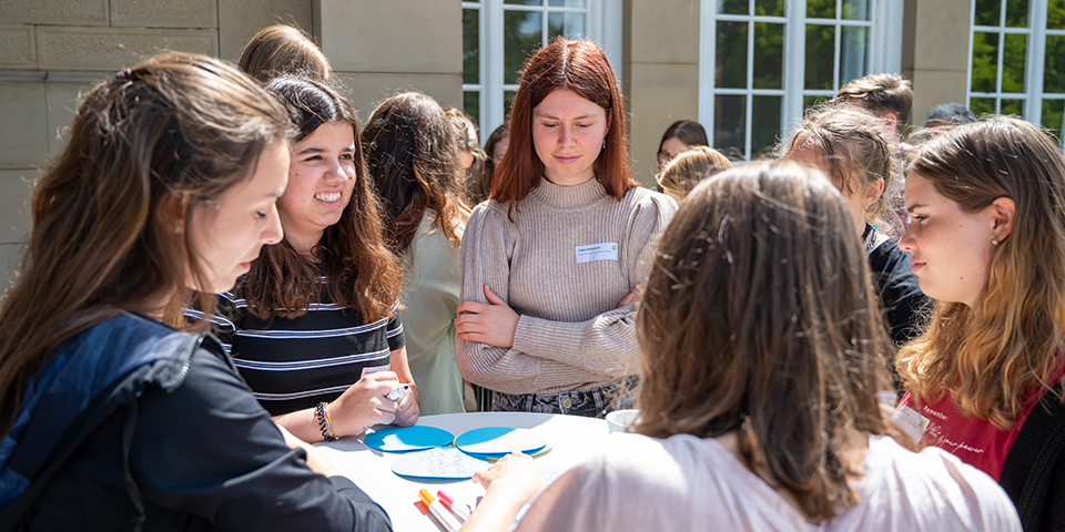 Mehrer Personen stehen an einem Tisch zusammen und erörtern das Thema des Workshops Ernährung.