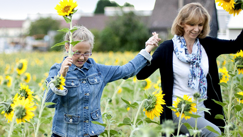 Frau mit Kind in einem Sonnenblumenfeld.