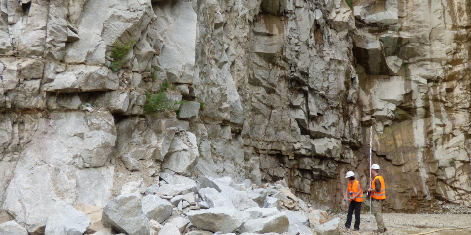 Zwei Personen in Warnweste und mit Schutzhelm in einem Granit-Steinbruch.