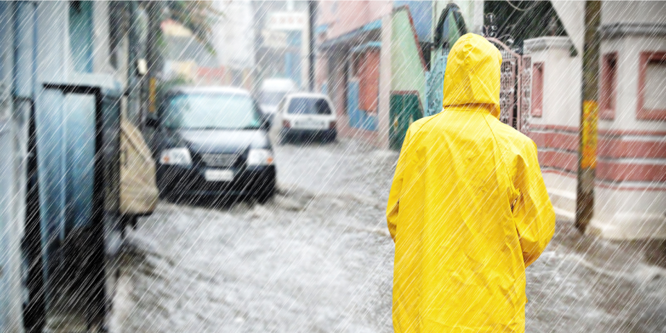 Person im gelben Regenmantel bei Hochwasser und Starkregen.